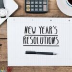 A notebook on a table reads: New Year's Resolutions